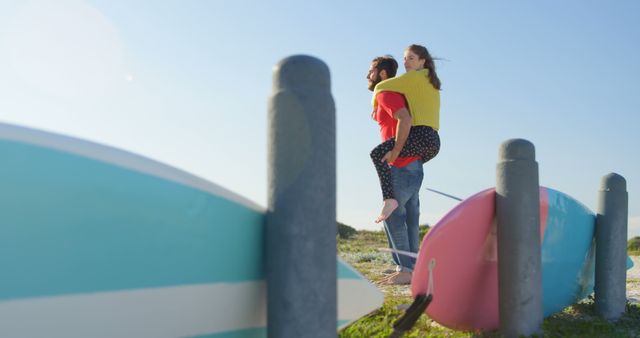 Happy Couple Piggybacking Near Surfboards by the Beach - Download Free Stock Images Pikwizard.com