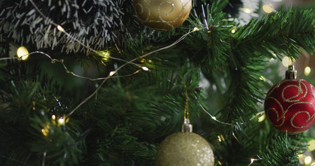 Green Christmas tree with gold and red ornaments. Lights and tinsel enhance the festive setting. Perfect for holiday greetings, decoration ideas, and festive season promotions.