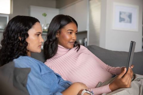 Diverse Friends Relaxing Together Using Tablet in Modern Living Room