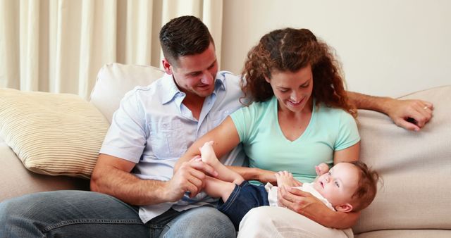 Loving Family Sitting on Couch with Parents Tickling Baby - Download Free Stock Images Pikwizard.com