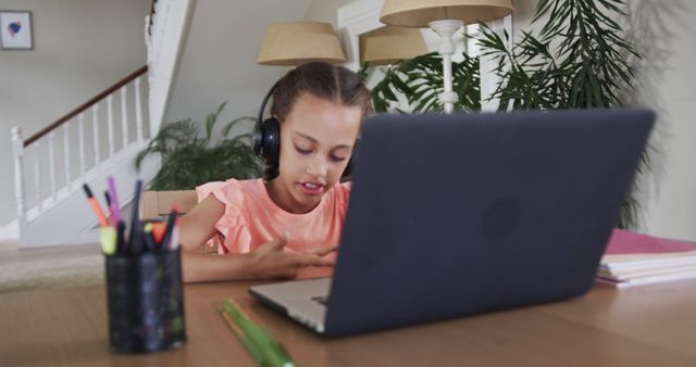 Biracial girl learning online using laptop at home. Lifestyle, childhood, communication, online education, learning and domestic life, unaltered.