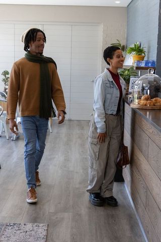 African american couple ordering pastries at modern wood counter in bright cafe