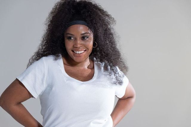 Confident woman smiling in white ribbed t-shirt with headband, casual headshot
