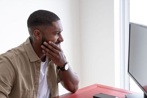 Man focusing on computer work at red desk in minimalist home office