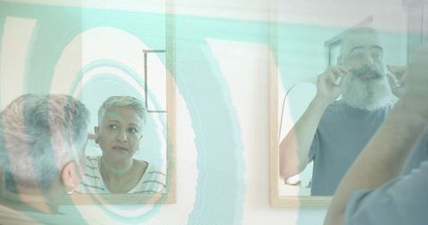 Mature couple grooming together at home vanity with turquoise mirror reflection