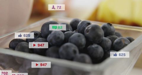 Macro closeup blueberries in clear glass bowl with social media engagement icons overlay