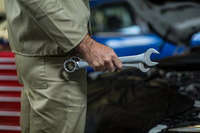 Mechanic Holding Wrench in Auto Repair Shop - Download Free Stock Photos Pikwizard.com