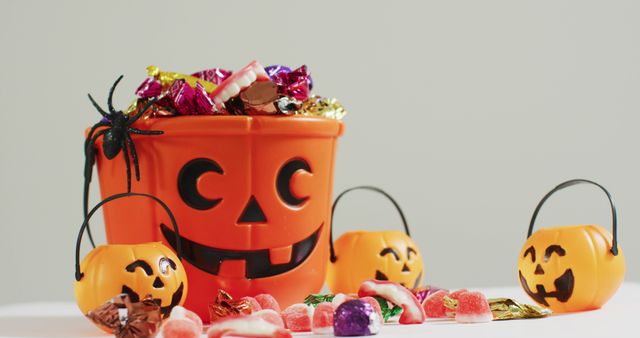 Scary halloween pumpkin printed bucket full of candies against grey background - Download Free Stock Photos Pikwizard.com