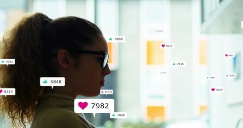 Young woman wearing glasses viewing floating social media engagement metrics on glass