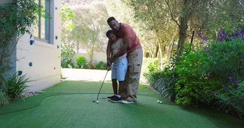 Father Teaching Son Golfing Skills at Home Garden Green