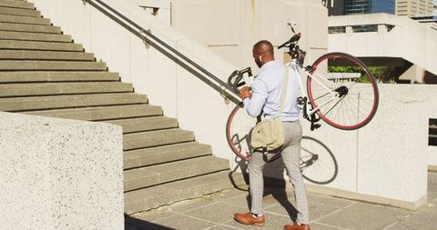 Businessman Carrying Bicycle Up Urban Stairs in City