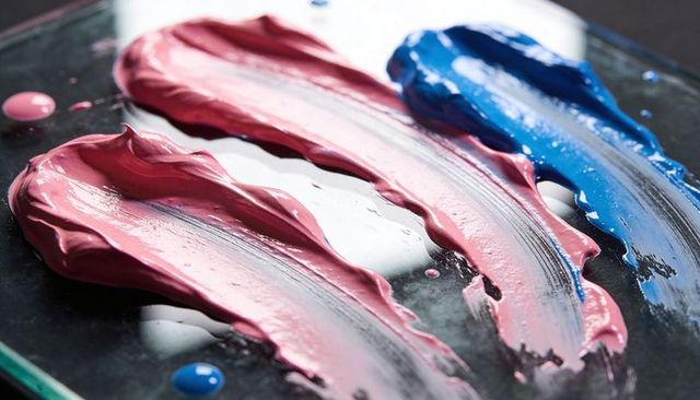 Thick pink and blue paint smears creating glossy texture on glass palette