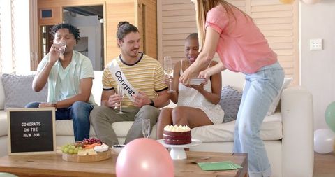 Joyful friends celebrating job success with champagne and cake