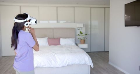 Woman Using VR Headset in Modern Bedroom with Minimalist Interior