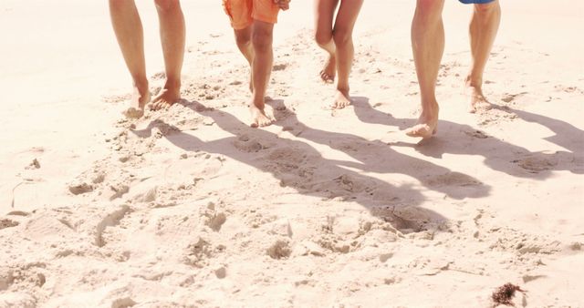 Family walking on sandy beach barefoot enjoying summertime. Ideal for family vacation promotions, travel brochures, and advertisements emphasizing togetherness and relaxation. Great for showcasing beach destinations and family leisure activities.