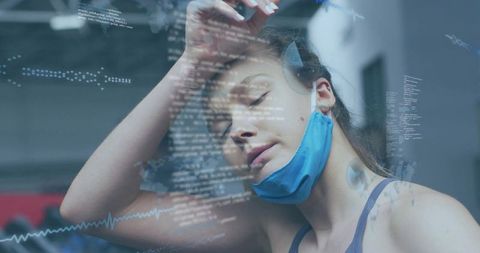 Exhausted gym athlete recovering after intense workout wearing mask and headphones