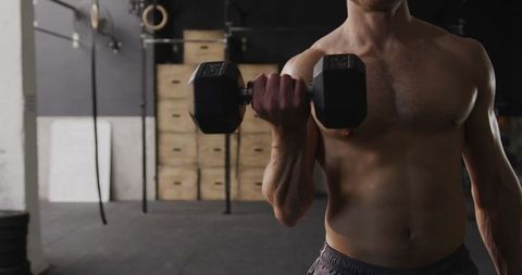 Caucasian Male Performing Intense Dumbbell Curls in Gym