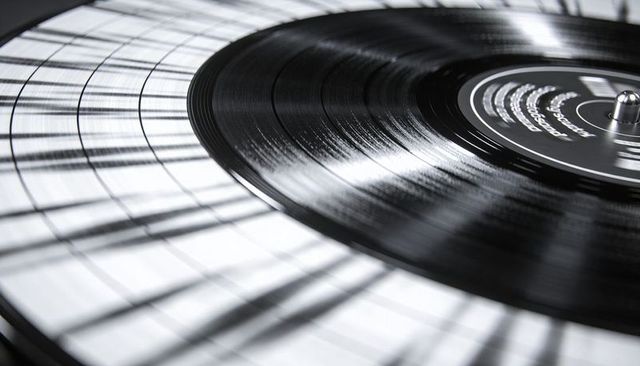 Spinning black vinyl record on concentric grid mat with dramatic light and motion