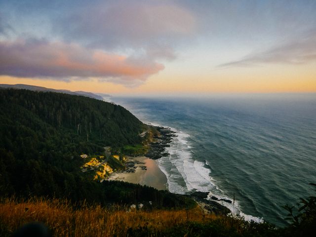 Capturing the vibrant colors of the sky at sunset over a coastal landscape with waves crashing against cliffs and an adjoining forest. Ideal for travel blogs, nature websites, and relaxation content.