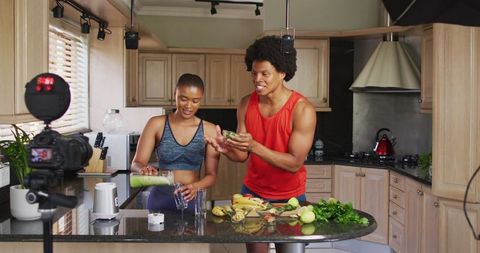 Diverse friends vlogging healthy cooking in modern kitchen