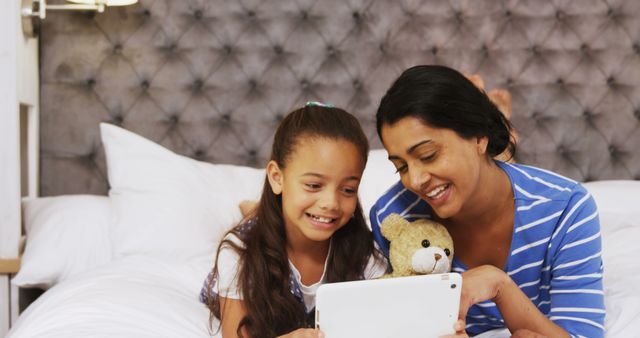 Mother and Daughter Using Tablet in Bed Smiling - Download Free Stock Images Pikwizard.com