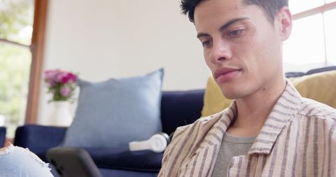 Focused Young Man Using Smartphone at Home in Relaxed Mood