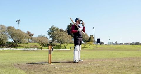 Cricketer relaxing on pitch in full gear