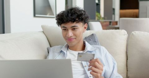 Young Man Shopping Online with Credit Card in Modern Home