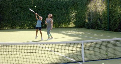 Mother and Daughter Tennis Session on Sunny Outdoor Court