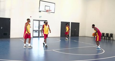 Energetic Basketball Players Practicing on Indoor Court