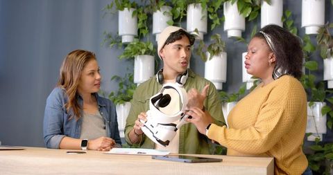 Multicultural team examining white vr headset during design collaboration