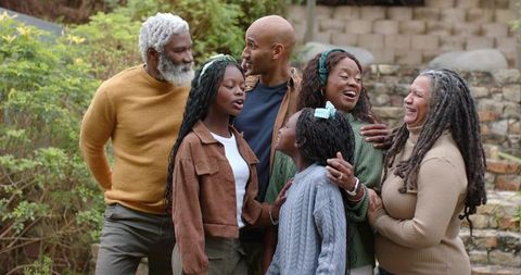 Multigenerational family laughing and chatting on terraced garden stone steps, togetherness