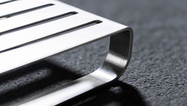 Resting brushed stainless steel slotted rack on dark stone surface, kitchen accessory
