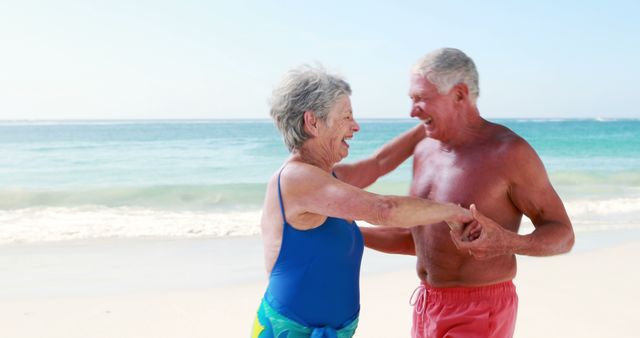 Senior couple dancing on sandy beach, showing happiness and romance in their retirement years. Ideal for advertising senior living, retirement communities, health and wellness, vacation destinations, or active lifestyle content.