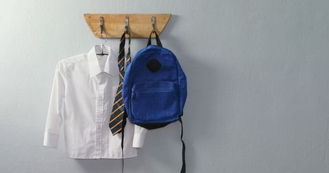 School uniform shirt and blue backpack on wooden hook