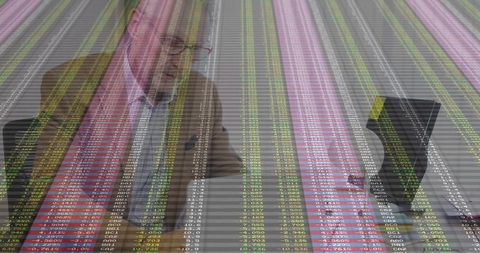 Senior analyst analyzing market data overlaying office workspace with laptop and documents