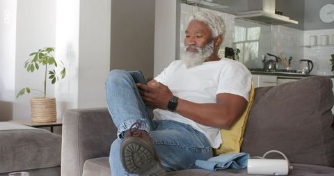 Relaxed Senior Man Browsing Tablet in Cozy Living Room