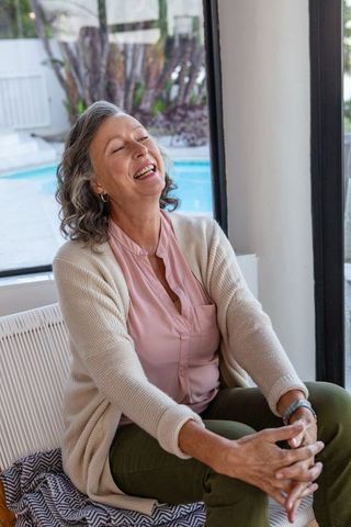 Senior Woman Laughing with Bright Natural Sunroom and Pool