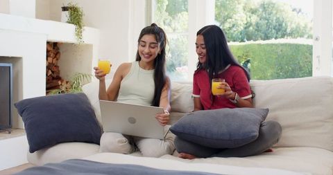 Two Friends Relaxing at Home with Juice and Laptop
