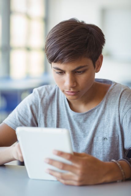 Attentive schoolboy using digital tablet in classroom at school