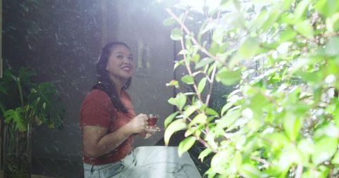 Woman enjoying tea by sunny window in indoor garden ambiance
