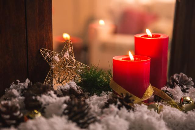 Red candles and a golden star ornament create a cozy and festive atmosphere. Pine cones and fake snow add a touch of winter charm, perfect for holiday-themed projects, greeting cards, or seasonal advertisements.