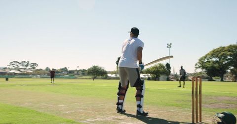 Indian batsman playing cricket in park, bowler delivering ball, running between wickets