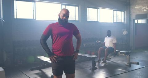 African men working out in industrial gym, bearded man in red wearing compression sleeve
