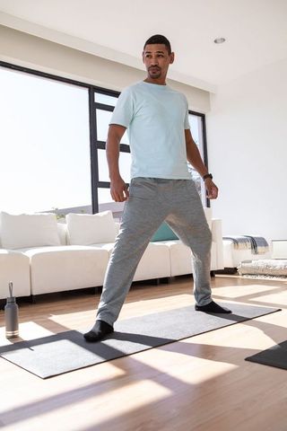 Man stretching on yoga mat in sunlit living room for wellness