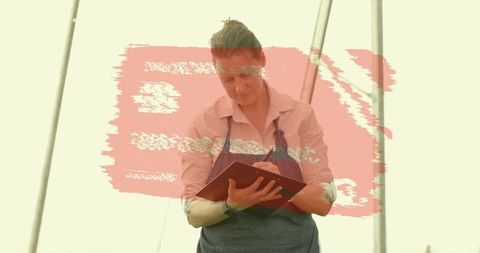 Gardener wearing apron noting observations inside greenhouse