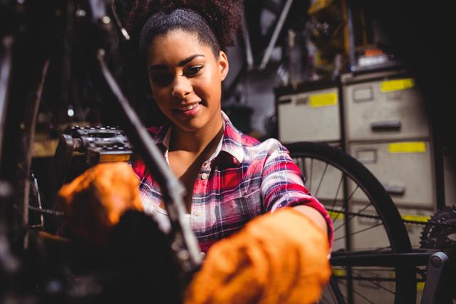Woman mechanic repairing a bicycle in her workshop, showcasing technical skills and hands-on work. Ideal for use in articles or advertisements related to bicycle repair services, mechanical skills, female professionals in technical fields, or DIY repair guides.