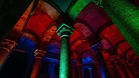 Tilting camera revealing vaulted crypt columns with dramatic multicolor lighting