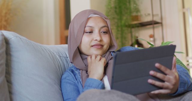 Relaxed Young Muslim Woman Using Tablet on Couch at Home - Download Free Stock Images Pikwizard.com