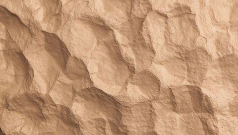 Macro sandstone relief texture showing rounded depressions and ridges with soft sidelight